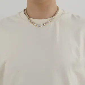 Dettaglio di una collana tennis dorata con zirconi tondi indossata sul collo di un modello