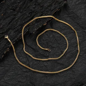 Macro detail of a 2mm gold Franco chain necklace with a lobster clasp on black background