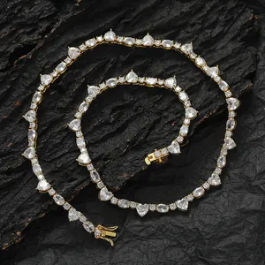 Parure collier et bracelet tennis dorés avec pierres cœur et rondes sur fond de pierre