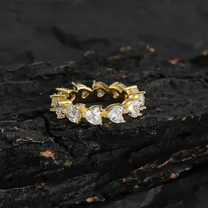 Iced out gold eternity ring with 5mm heart shaped cubic zirconia stones on dark wood