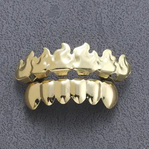 Macro view of gold hip hop grills featuring top row flame shape design on textured background
