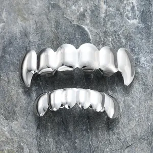 Set grillz hip-hop in argento lucido con design a canini affilati su sfondo di roccia
