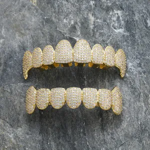 Iced out gold hip hop grillz set with sparkling white zircon stones on stone background