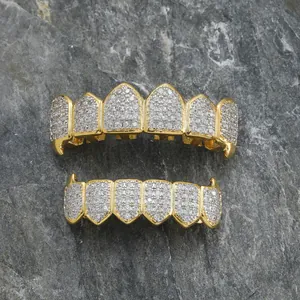 Σετ χρυσά grillz hip hop με κρύσταλλα micro-pave σε φόντο από σκούρα πέτρα