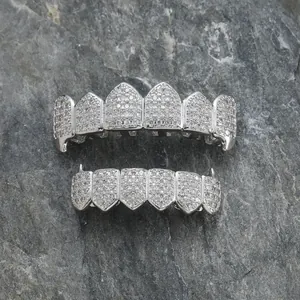Ασημένιο σετ hip hop grillz με ζιργκόν πέτρες σε σκούρο πέτρινο φόντο