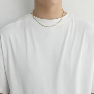 Close-up of a 2mm gold tennis chain with cubic zirconia worn by a model on white tee