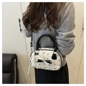 Detail of white wrinkled bag with black bows, pearl pendant and adjustable shoulder strap
