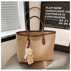 Detail of khaki pebbled leather tote bag with dark brown handles and a bear charm
