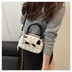 Detail of white bow print handbag featuring pearl chain and black leather handles