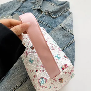 Détail d'une anse rose confortable sur un sac à main blanc plissé avec motif cupcake