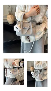 Detail of woven texture bucket bag with decorative buckle and plush pendant charm