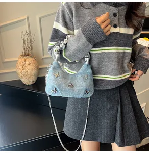 Détail du sac demi-lune en jean bleu clair avec papillons argentés et chaîne