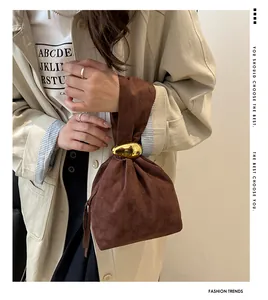 Detail of a brown faux suede bucket bag with a stylish irregular gold metal ring handle
