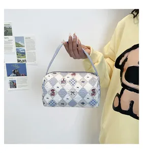 Détail d'un sac à main matelassé blanc avec broderie ours bleu et anses en tissu bleu