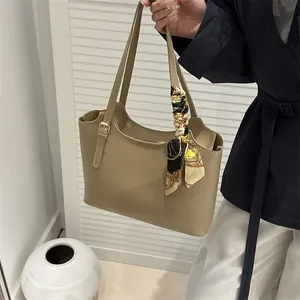 Detail of khaki tote bag handle with elegant printed silk scarf and matte leather texture