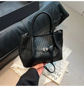 Detailed view of black woven texture on fashionable bucket bag with detachable shoulder strap
