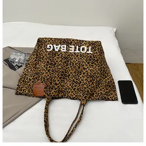 Detail of leopard print tote bag with white TOTE BAG lettering and brown leather tag