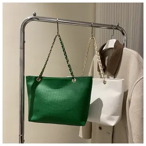 Detail of crocodile-textured leather tote bags with elegant gold metal chain straps