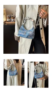 Détail du sac demi-lune en denim bleu avec papillon argenté et poignée froncée
