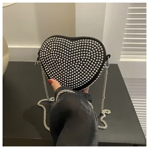 Macro view of a heart-shaped black crossbody bag with silver studs and chain strap
