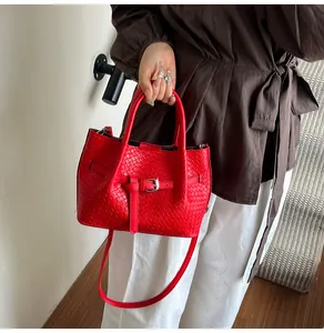 Detail shot of a vibrant red bucket bag featuring woven texture and metallic buckle accents