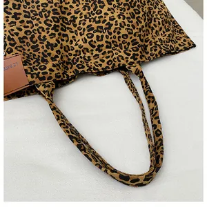 Close-up of leopard print canvas tote bag with brown leather brand tag and sturdy handle