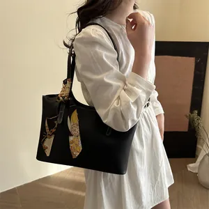 Detail of black leather tote bag with elegant floral scarf handle on a shoulder