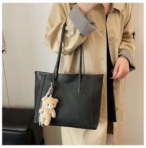 Detail of black pebbled leather JK backpack with cute brown bear charm on side