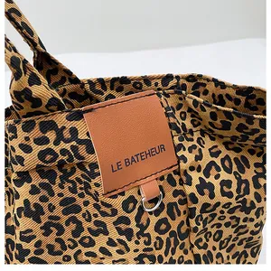 Detail of leopard print canvas tote with leather patch and silver metal D-ring