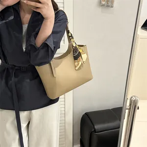 Detail of khaki tote bag with patterned silk scarf handle and matte leather finish