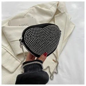 Detail of heart-shaped black crossbody bag with silver studs and chain strap