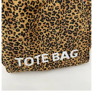 Close-up of leopard print canvas tote bag featuring white TOTE BAG text print