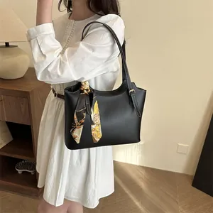Detail of black leather tote bag with white contrast stitching and a vintage silk scarf handle