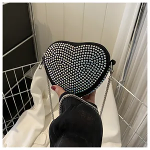 Detail of heart-shaped crossbody bag with shimmering colorful rhinestones and silver chain