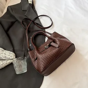 Brown woven bucket bag with adjustable shoulder strap and leather belt buckle detail