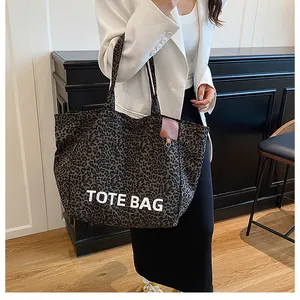 Close-up of leopard print tote bag with TOTE BAG text and brown leather nameplate