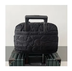Détail du sac de voyage noir matelassé avec cœurs montrant le passant pour valise