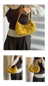 Détail d'un sac hobo jaune avec pendentif en forme de cœur et nœud décoratif