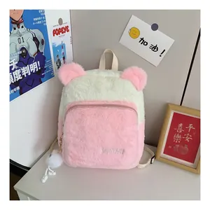 Detail of pink and white plush backpack with bear ears and pom-pom charm on a desk