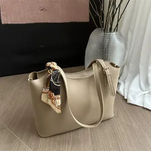 Detail of a large beige tote bag with long shoulder strap and silk scarf accessory