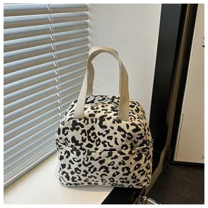 Detail of leopard print corduroy tote bag showing woven handles and front pocket