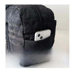 Détail d'un sac en nylon noir à surpiqûres en cœur montrant une poche latérale pratique