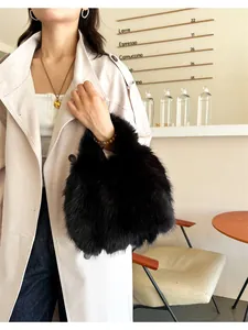 Détail d'un sac à main en peluche noire porté avec un manteau dans un café chic