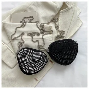 Detail of heart-shaped rhinestone crossbody bags with silver chain straps and sparkle finish