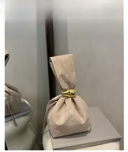 Detail view of khaki suede bucket bag featuring a large decorative gold metal ring handle