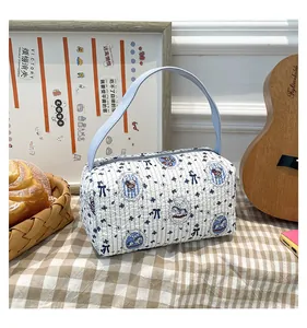 Détail d'un sac à main cylindrique matelassé aux motifs floraux et nœuds bleus élégants