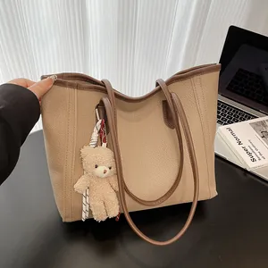 Minimalist khaki lychee leather tote bag with brown straps and plush bear charm