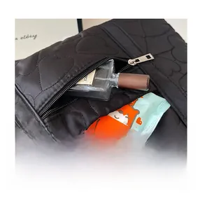 Vue détaillée de la poche zippée avant sur un sac bandoulière noir matelassé en cœurs