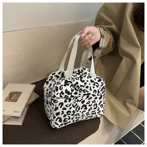 Detail of leopard print corduroy lunch bag featuring a side pocket and woven handle