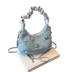 Sac à main en denim bleu clair avec papillons argentés et poignée métallique plissée